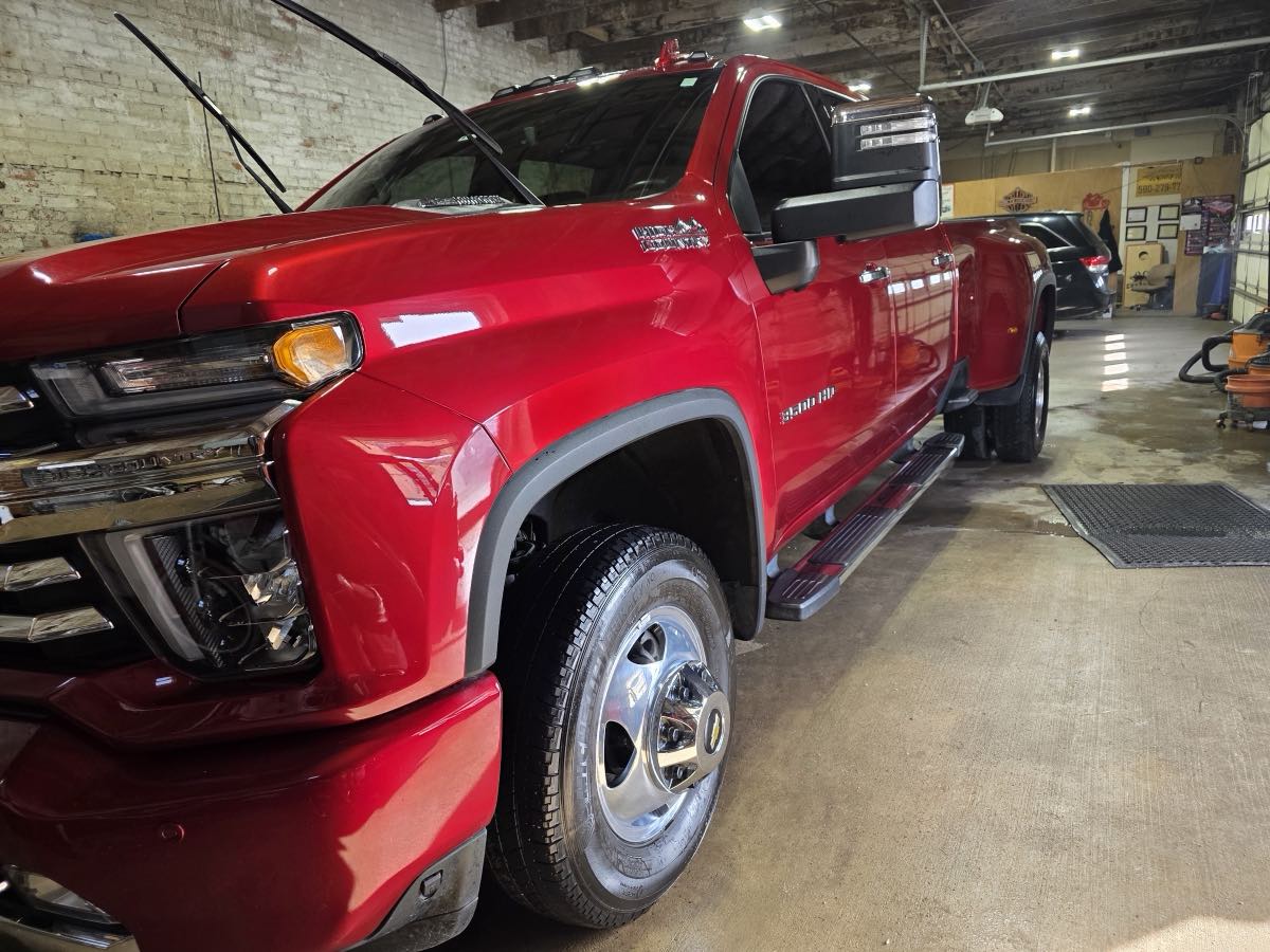 Freshly detailed red Chevy Silverado with a mirror finish inside the Platinum Custom Detailing shop